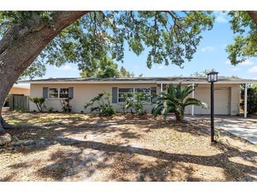 Charming single-story home featuring mature trees, inviting landscaping, and neutral exterior paint at 8696 118Th St, Seminole, FL 33772