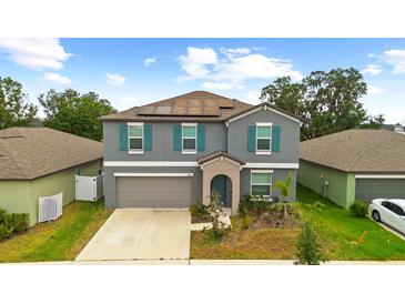 Charming two-story home with grey siding, teal shutters, manicured landscaping, and a two-car garage at 13380 Great Plains Dr, Riverview, FL 33579