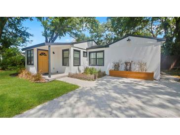 Charming home with a bright yellow front door, clean white exterior, and a modern driveway at 1715 N Alexander Rd, Tampa, FL 33603