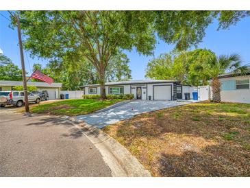 Charming home featuring lush landscaping, mature trees, and a freshly painted driveway leading to an attached garage at 8444 8Th N Way, St Petersburg, FL 33702