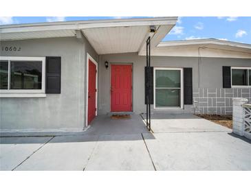 Home exterior with red front door, black shutters, and neutral gray paint at 10602 Camelia Dr, Port Richey, FL 34668