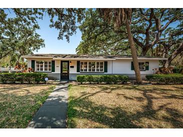 Charming single-story home featuring lush landscaping, a well-maintained lawn, and classic green shutters at 2880 81St N St, St Petersburg, FL 33710