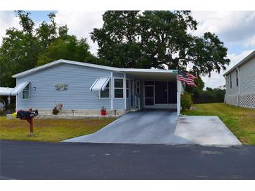 Charming single-story home with covered parking, manicured lawn, and patriotic American flag at 37643 Campo Ave, Zephyrhills, FL 33541