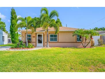 Charming single-story home with a lush green lawn, tropical landscaping, and a welcoming walkway to the front door at 4721 W Lawn Ave, Tampa, FL 33611