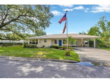 Charming single-story home featuring a metal roof, well-manicured lawn with a flagpole, and a convenient carport at 509 N Walker St, Plant City, FL 33563