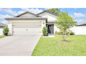 Well-maintained home featuring a two-car garage, manicured lawn, and fresh landscaping at 7099 Crested Orchid Dr, Brooksville, FL 34602