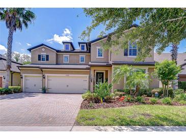 Stunning two-story home featuring a three-car garage, beautiful landscaping and a brick paved driveway at 11205 Lark Landing Ct, Riverview, FL 33569