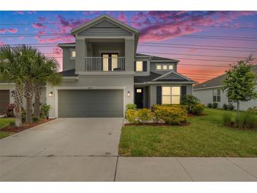 Charming two-story home with a balcony, a well-manicured lawn, and vibrant landscaping at 2693 Leafwing Ct, Palm Harbor, FL 34683