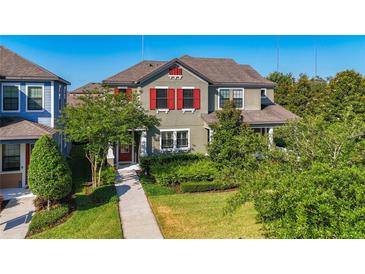 Charming two-story home featuring a landscaped yard, red shutters, and a welcoming front porch entrance at 5807 Circa Fishhawk Blvd, Lithia, FL 33547