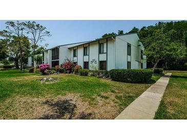 Charming two-story condo with lush landscaping and colorful flowers along the walkway at 1290 Pine Ridge E Cir # G1, Tarpon Springs, FL 34688