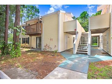Two-story condo with yellow siding, a small patio and a stairway to an upper unit at 134 Sycamore Ln # F, Oldsmar, FL 34677
