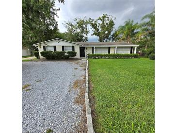 Charming single-story home featuring a well-maintained lawn, a rock driveway, and manicured shrubbery at 1412 Sunset Ln, Lutz, FL 33549