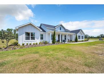 Beautifully landscaped lawn featuring a modern farmhouse with clean lines and manicured shrubbery at 14902 Sweat Loop Rd, Wimauma, FL 33598