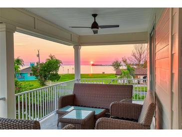 Inviting covered porch with wicker furniture to enjoy sunset and waterfront views at 3174 Sanibel Dr, Hernando Beach, FL 34607