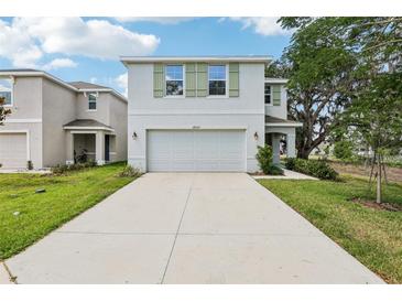 Two-story home featuring a two-car garage, tidy lawn, and charming green shutters at 36557 Night Strawberry Ct, Dade City, FL 33525