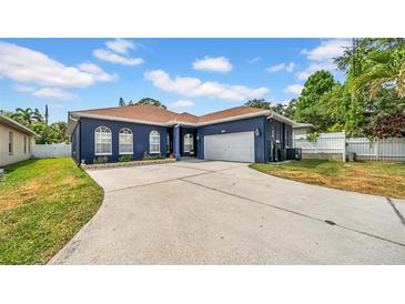 Charming single-story home with a blue exterior, arched windows, and a spacious driveway at 650 Arbor Ln, Largo, FL 33770