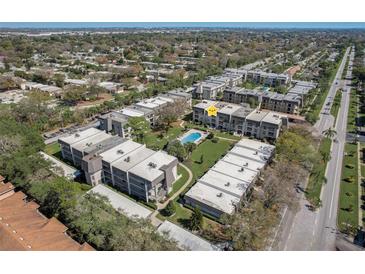 Aerial view of condo buildings with a community pool and well-maintained green spaces, and a road nearby at 8703 Bardmoor Blvd # 305, Seminole, FL 33777
