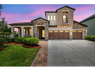 Elegant two-story home featuring stone accents, a three-car garage, and a beautifully landscaped front yard at 1796 Tonka Ter, Wesley Chapel, FL 33543