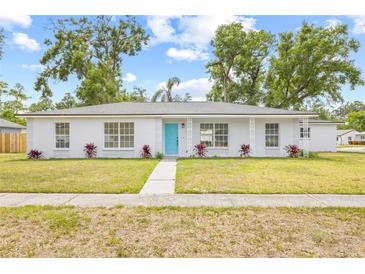 Charming one-story home features a vibrant turquoise door and a well-maintained lawn with manicured landscaping at 2901 Forestwood Dr, Seffner, FL 33584