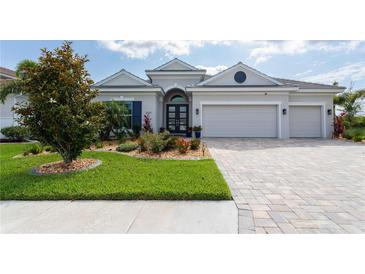 Beautiful single-story home with a three-car garage, paver driveway, manicured lawn, and mature trees at 3727 Wild Blossom Pl, Parrish, FL 34219