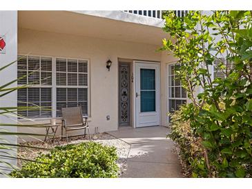 Charming condo entrance with a small seating area, well lit and landscaped at 402 Laurel Lake Dr # 104, Venice, FL 34292