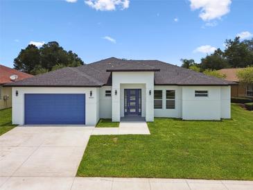 Beautiful, modern home with a blue garage door and a well-manicured lawn at 4260 Baudelaire Ct, Brooksville, FL 34604