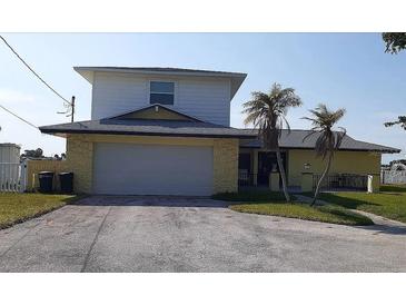 Two-story home featuring an attached two-car garage, palm trees, and a well-maintained front yard at 5930 Bahama N Way, St Pete Beach, FL 33706