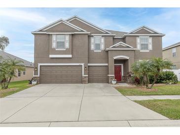 Charming two-story home with a three-car garage and a well-manicured lawn at 621 Washita Stone Dr, Ruskin, FL 33570