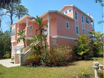Charming two-story home boasts a stucco exterior, manicured lawn, and lush tropical landscaping at 6926 Mccray Dr, Hudson, FL 34667