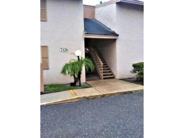 Exterior view of the building featuring light stucco and an entrance staircase at 7526 Needle Leaf Pl # 29, Tampa, FL 33617