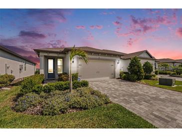 Charming single-story home featuring a well-manicured lawn and a brick-paved driveway at 10418 Spring Tide Way, Parrish, FL 34219
