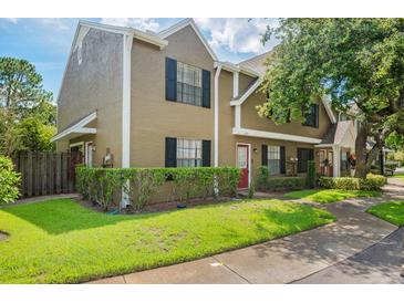 Inviting home with lush green lawn, mature trees, black shutters, and a charming red front door at 16504 Lake Brigadoon Cir, Tampa, FL 33618
