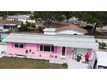 Single story home, painted pink, with white trim, landscaping, and grey roof in a quiet neighborhood at 12425 Ridge Rd, Largo, FL 33778