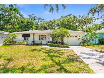 Charming single-story home featuring lush landscaping, mature trees, and a well-maintained front lawn at 417 Broadway, Dunedin, FL 34698