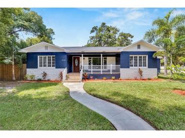 Charming blue two-story home featuring a welcoming front porch and well-maintained lawn at 6110 N Suwanee Ave, Tampa, FL 33604
