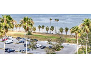Scenic view of a parking lot adjacent to a beach with palm trees and ocean, offering convenient access to waterfront amenities at 1120 N Shore Ne Dr # 804, St Petersburg, FL 33701