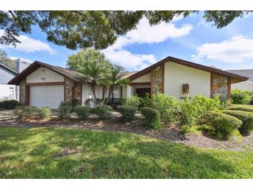 Charming single-Gathering home featuring stone accents, a manicured lawn, and lush landscaping at 16517 Norwood Dr, Tampa, FL 33624
