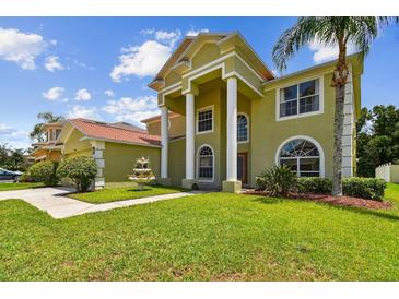 Inviting front exterior with large pillars, well-manicured lawn, and a decorative water fountain feature at 27012 Sea Breeze Way, Wesley Chapel, FL 33544