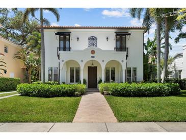 Beautiful white stucco two-story home with arched porch, tile roof, lush landscaping and brick walkway at 3212 W Fountain Blvd, Tampa, FL 33609