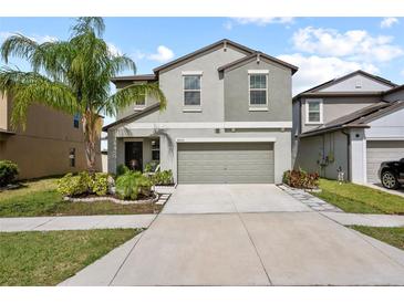 Two story home with a two car garage, beautiful landscaping and a palm tree in the front yard at 4533 Eternal Prince Dr, Sun City Center, FL 33573