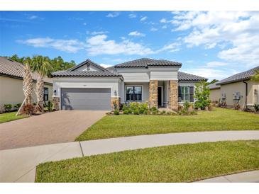 Charming single-story home with well-manicured lawn, stone accents, tile roof, and paver driveway at 4831 Rosatti Rd, Wesley Chapel, FL 33543