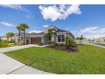 Charming single-story home with a well-manicured lawn, palm trees, and a two-car garage at 5924 Fieldmoor Ct, Palmetto, FL 34221