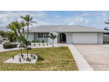 Charming single-story home with a well-manicured lawn, palm trees, and a two-car garage at 7092 S Shore S Dr, St Petersburg, FL 33707