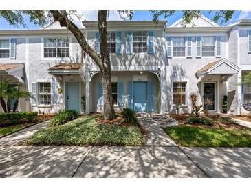 Inviting townhome with light blue shutters, beautiful landscaping, and a mature shade tree at 8612 Hunters Key Cir, Tampa, FL 33647