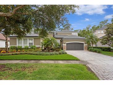 Beautiful home with lush landscaping, brick driveway, and a well-maintained front yard at 14851 Tudor Chase Dr, Tampa, FL 33626