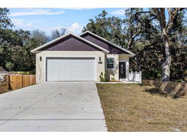 Charming home features a two-car garage, a well-maintained lawn, and a welcoming entrance, all set beneath mature shade trees at 16519 Us Highway 41, Spring Hill, FL 34610