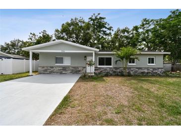 Charming single-story home with a well-manicured lawn, gray paint and stone accents at 3106 Ash Ct, Dunedin, FL 34698