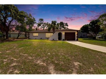 A warm sunset complements this cozy home, featuring an arched entry and manicured landscaping at 3344 Blythe Ave, Spring Hill, FL 34609
