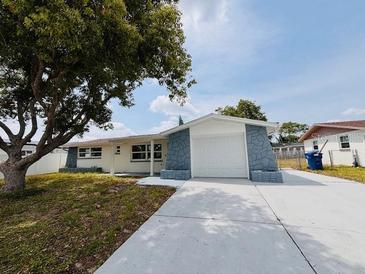 Charming single-story home with stone accents and a well-maintained front yard under a blue sky at 6046 7Th Ave, New Port Richey, FL 34653