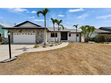 A quaint, single-story home with an attached garage, stone facade, and tropical landscaping at 743 Kingston Ct, Apollo Beach, FL 33572